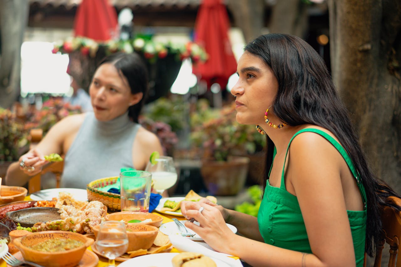 Two women seated at a table, enjoying a meal together, with plates of food in front of them.